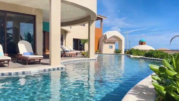 Zona de piscina en un resort, con sillones de descanso y vista despejada al océano.