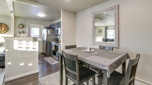 A dining area with a table set for four, a kitchen in the background, and a clock on the wall. - Updated Townhome: Near Airport & Shopping! (Anchorage)