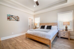 A bedroom with a wooden bed, two bedside tables, a ceiling fan, and a wall-mounted artwork of paddles. - New waterfront house on Lake Norman/private dock (Troutman)