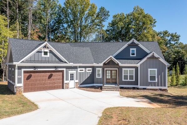 A two-story house with a garage, a front porch, and a small attached shed. - New waterfront house on Lake Norman/private dock (Troutman)