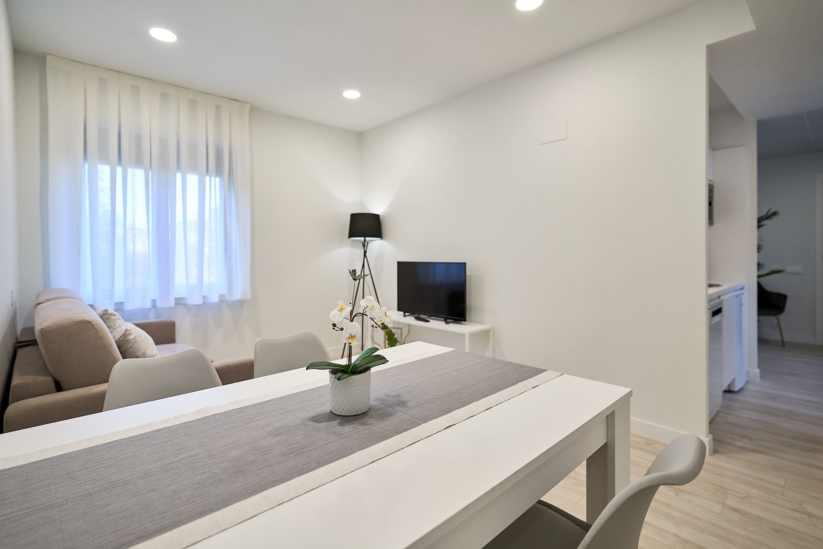 Una sala de estar moderna con una mesa de comedor, sofá y televisor.