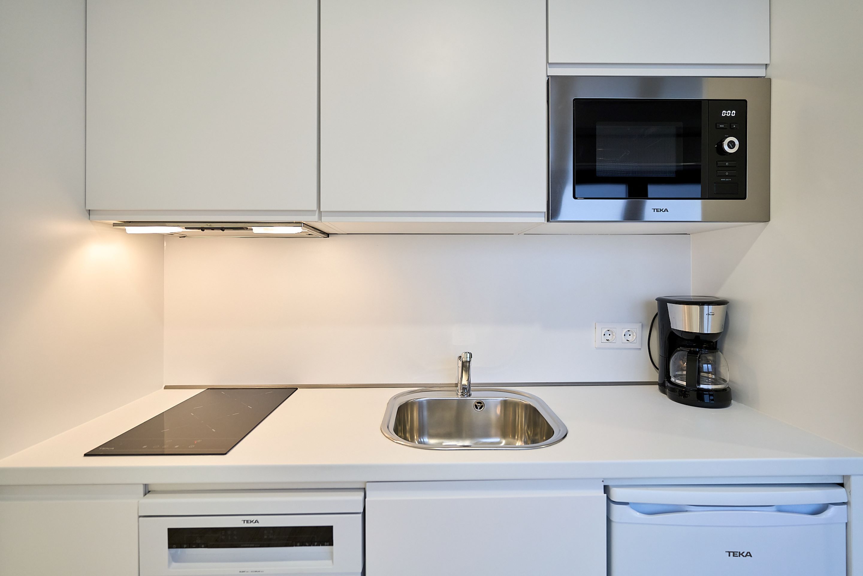 Una cocina moderna con microondas integrado, cafetera y lavavajillas.
