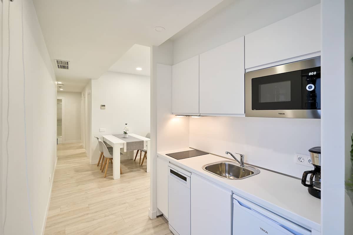A modern kitchen with white cabinetry, a built-in microwave, and a dishwasher.