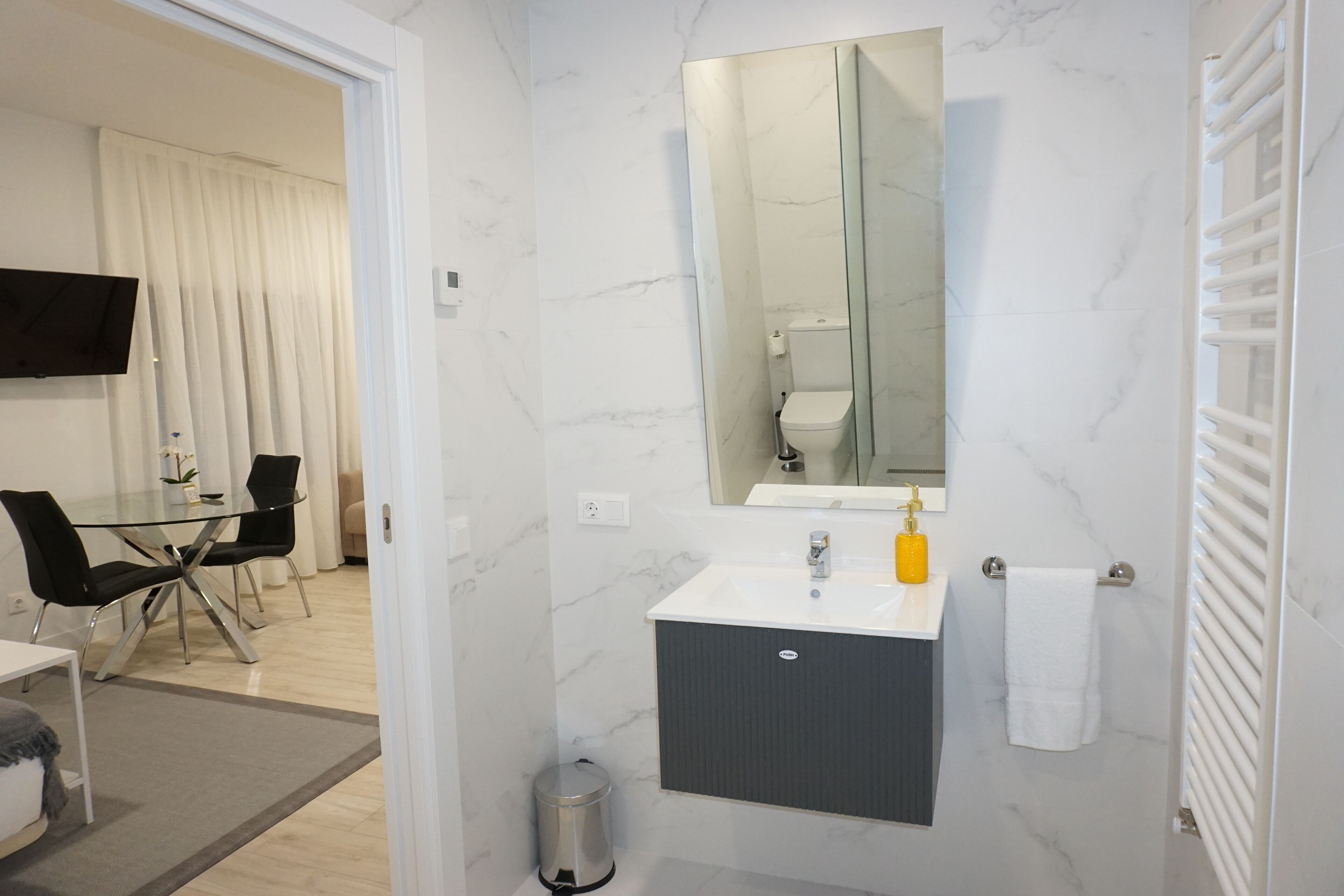 Une salle de bain moderne avec un lavabo en marbre blanc, un miroir et un porte-serviettes.