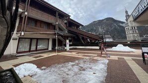 Un hotel con facciata in legno, una zona esterna coperta e montagne sullo sfondo.