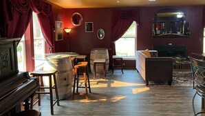 Una habitación acogedora con un piano, barriles de madera, un sofá y una chimenea.