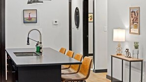 A modern kitchen with a central island, a dining area with chairs, pendant lights, and wall-mounted artwork. - Mid-Century 3 BR In Heart of Downtown Lex (Lexington)