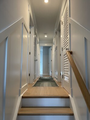 Stylish hallway with a clean, contemporary design, featuring a wooden staircase and decorative molding.