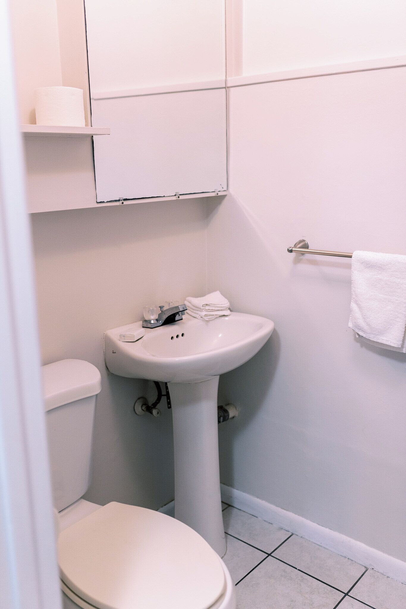 Ein kleines, sauberes Badezimmer mit Toilette, Waschbecken und Handtuchhalter.