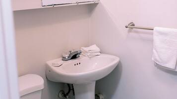 Ein kleines, sauberes Badezimmer mit Toilette, Waschbecken und Handtuchhalter.