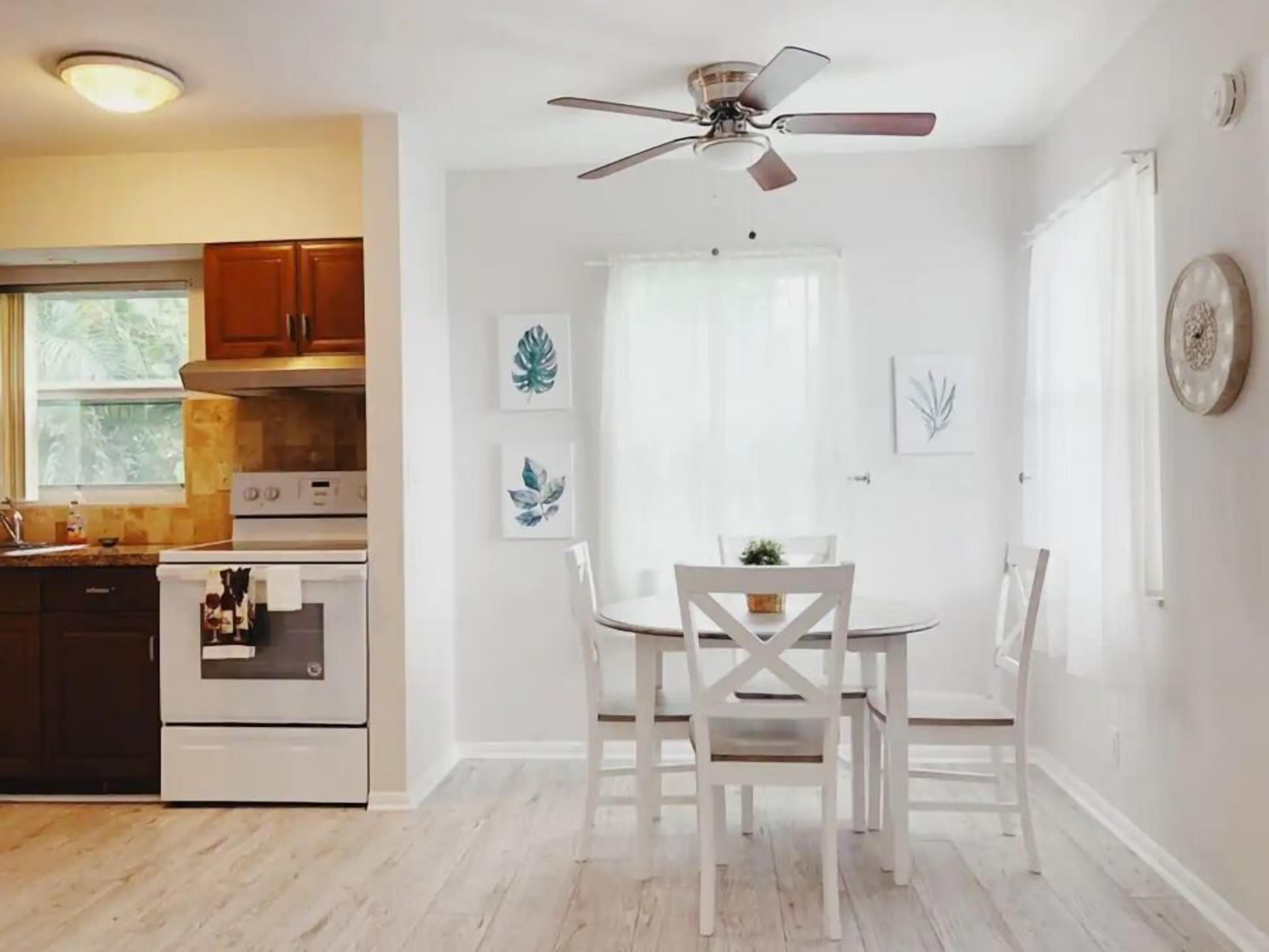 Una cocina con armarios blancos, estufa y ventilador de techo.