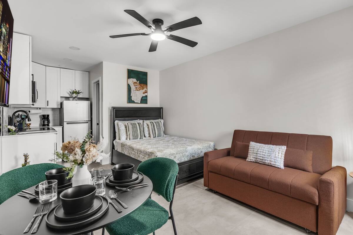 A modern, compact living space with a kitchenette, a dining area, and a sofa.