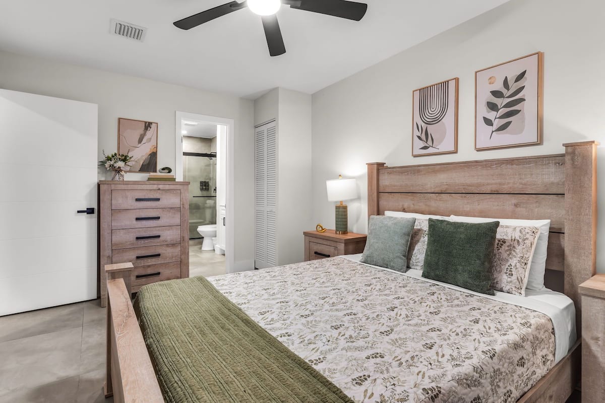 A bedroom with a bed, dresser, nightstand, and ceiling fan.