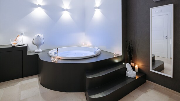 A modern bathroom with a freestanding bathtub, a vanity with a mirror, and a door. - Suite1212 Rattazzi (Monopoli)
