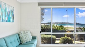 A room with a large window offering a view of the beach and ocean. - Mariners 3 - The closet apartment to Mollymook Beach, you can almost touch it! (Mollymook)