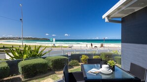A balcony with a glass table, chairs, and a view of the beach. - Mariners 3 - The closet apartment to Mollymook Beach, you can almost touch it! (Mollymook)