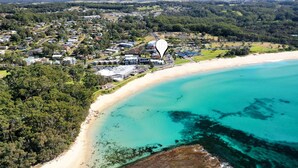 An aerial view of a coastal town with a beach, residential areas, and a prominent hotel with a large parking lot. - Mariners 3 - The closet apartment to Mollymook Beach, you can almost touch it! (Mollymook)
