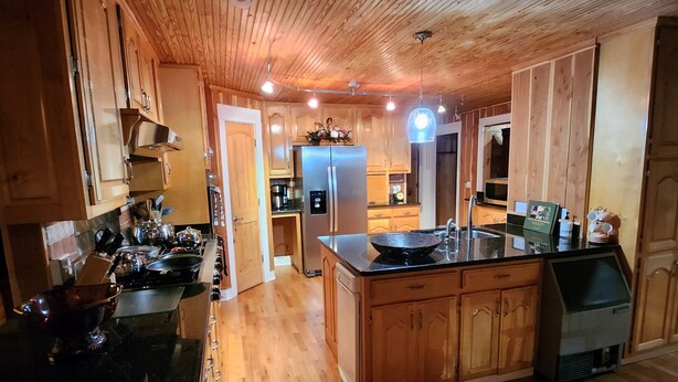 A spacious kitchen with wooden cabinets, a central island, and a stainless steel refrigerator.