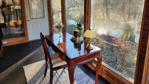 A dining area with a wooden table, chairs, and a view of a forest through large windows.