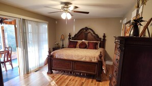 A bedroom with a wooden bed, a ceiling fan, and a dresser.