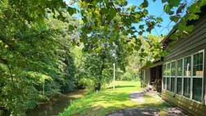 A riverside property with a wooden deck, a covered outdoor area, and a view of a river.