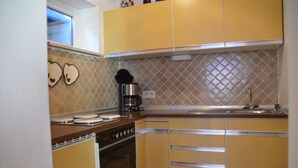 Een keuken met gele kastjes, een fornuis, een koffiezetapparaat en een decoratieve spatwand.