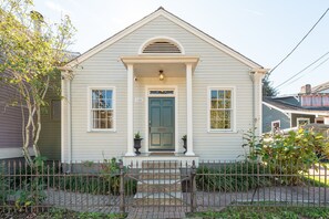A small, single-story house with a green door, white trim, and a small porch with a railing. - Family Friendly 3BR w Parking in Historic Neighborhood, Near French Quarter (New Orleans)