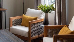 Una habitación acogedora con un sofá, dos sillones, una lámpara de pie, una planta en maceta y una ventana con cortinas.