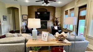 A living room with a wooden coffee table, two red vintage suitcases, a floor lamp, a ceiling fan, and a mounted deer head. - Farm to Beach in 15 Minutes (Panama City Beach)