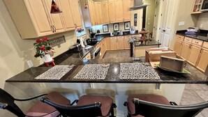 A modern kitchen with a large island, wooden cabinets, and pendant lights. - Farm to Beach in 15 Minutes (Panama City Beach)