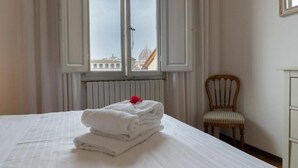 Ein Hotelzimmer mit Bett, Sessel und Fenster mit Blick auf Gebäude.