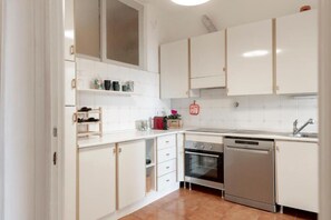 Una cocina con armarios blancos, estufa, horno y lavavajillas.