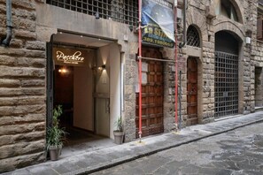 Un edificio de piedra con la entrada de una pizzería, una puerta de madera y una reja metálica.