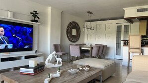 En moderne stue med et fladskærms-tv, et træbord og et spiseområde med stole og bord.
