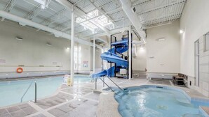 An indoor swimming pool with a blue water slide and a hot tub area. - Mountain Getaway for Families &Groups WATERSLIDE!! (Canmore)