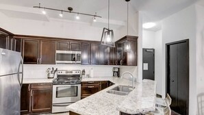 A modern kitchen with dark wood cabinets, stainless steel appliances, a granite countertop, and pendant lighting. - Mountain Getaway for Families &Groups WATERSLIDE!! (Canmore)