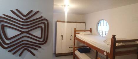 A bedroom with a bunk bed, a wardrobe, a decorative wall piece, and a small rug.