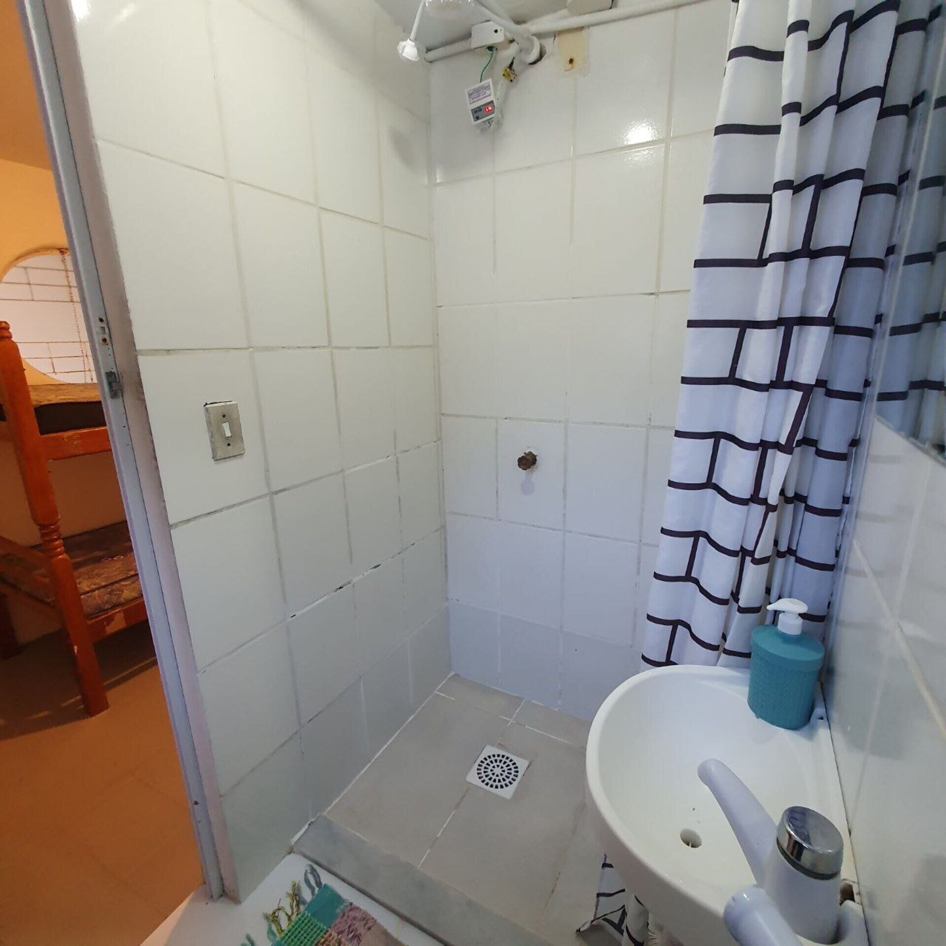 A small, tiled bathroom with a shower, a sink, and a toilet.