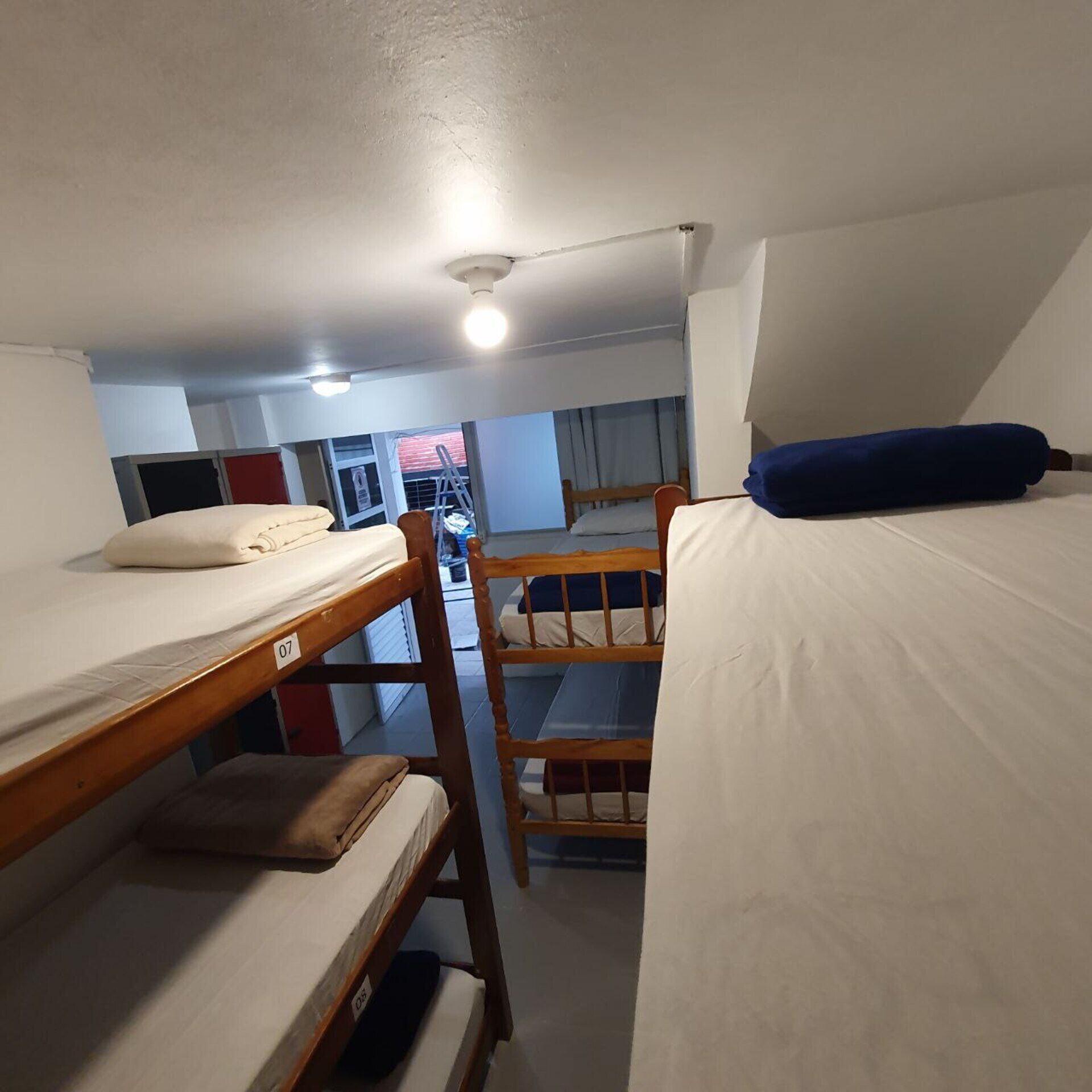 Un dormitorio con literas, una escalera y una pequeña zona de kitchenette.