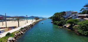 Ein Fluss mit einem Boot, einem Sandstrand und Gebäuden am Ufer.