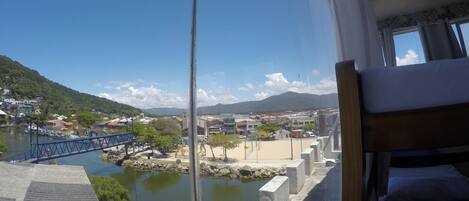 A room with a view of a town, a bridge, and a body of water.