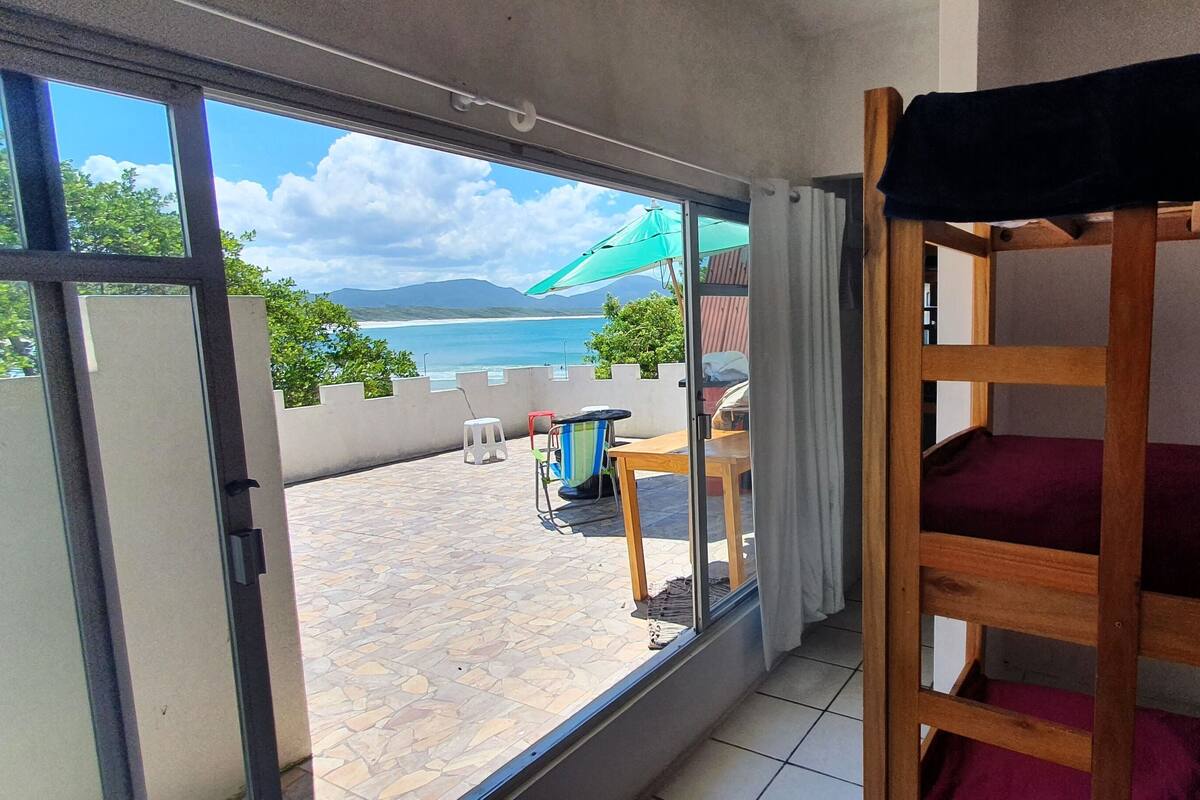 Une chambre avec un lit superposé, une vue sur la mer et un espace patio avec une table et des chaises.