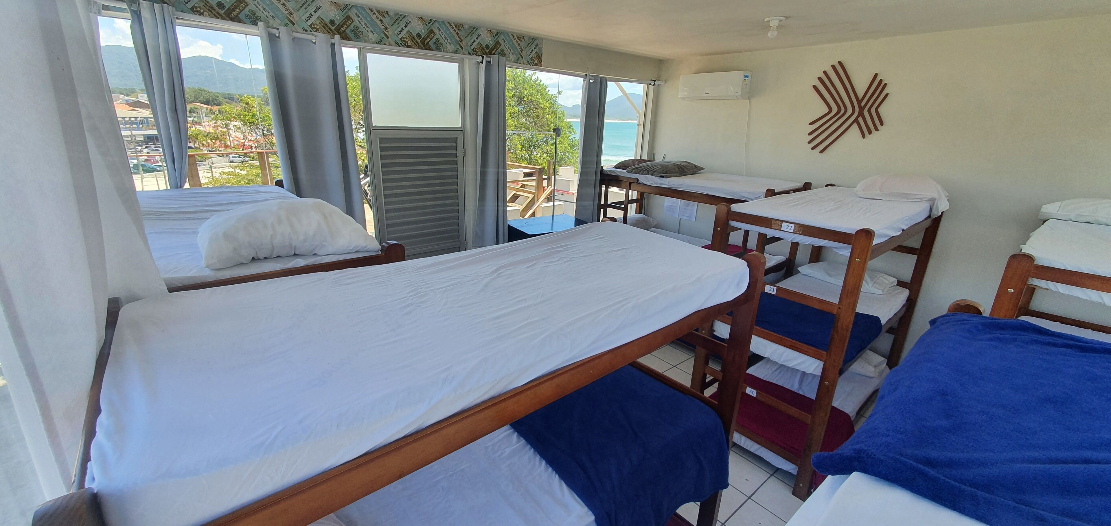 Une chambre avec des lits superposés, une fenêtre avec des rideaux, un appareil de climatisation et une vue sur l’extérieur.