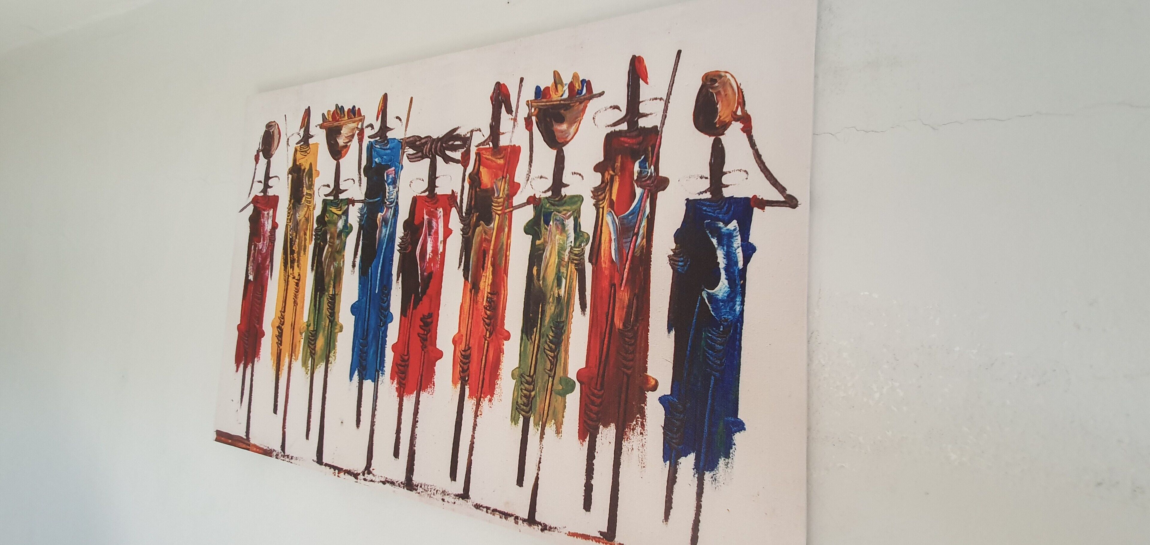 A painting of abstract figures with colorful attire and staffs on a white wall.