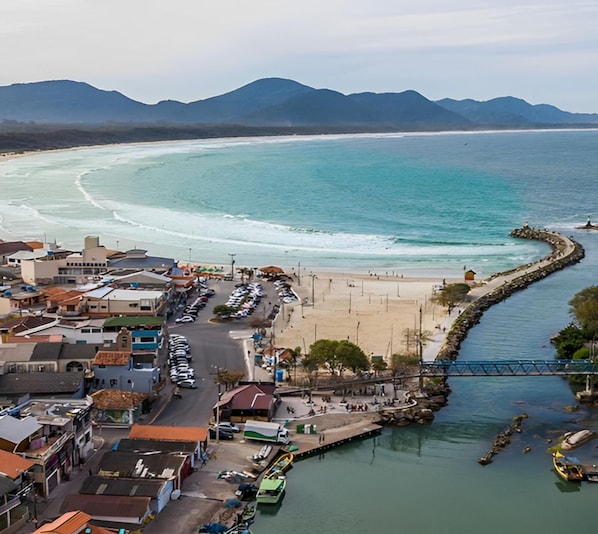 Eine Küstenstadt mit Strand, einer Straße, die zum Strand führt, und einer Brücke über einem Wasserweg.