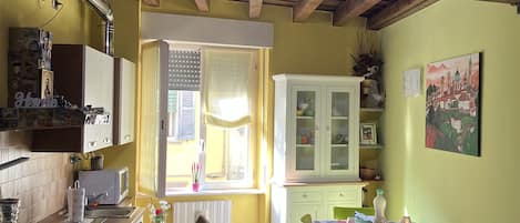 A cozy kitchen with wooden beams, a dining area with chairs, and a window letting in natural light.