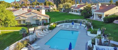 Zona residencial con piscina, sillones de descanso y vistas a montañas.