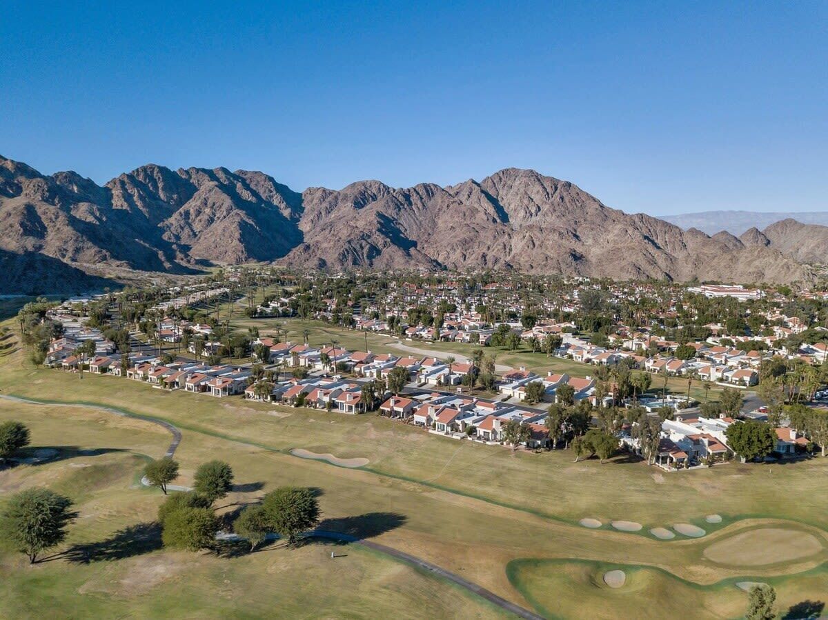 An aerial view of a residential area with houses, roads, and a golf course.