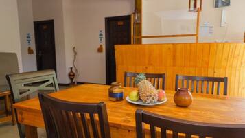 A wooden dining table with chairs, a pineapple, apples, and a vase.