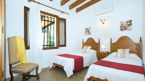 A bedroom with two beds, a wooden chair, a window with curtains, and a wall-mounted air conditioner. - Bacana, Finca 5StarsHome Mallorca (Puerto Pollensa)